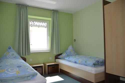 a small bedroom with two beds and a window at Ferienwohnungen Landgasthaus Janshen in Ellscheid