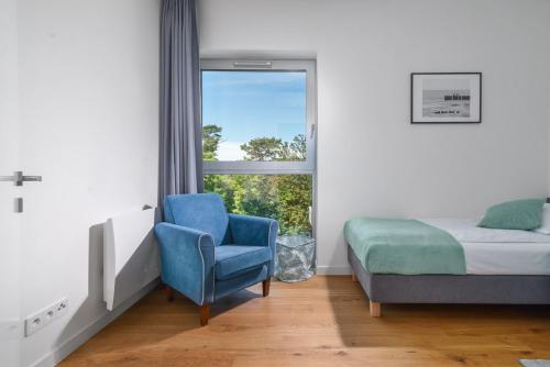 een slaapkamer met een bed, een stoel en een raam bij Jurata Residence in Jurata