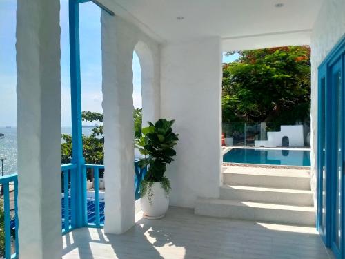 une maison blanche dotée d'une terrasse couverte avec une plante en pot dans l'établissement SUNTORINI BOUTIQUE HOTEL, à Vung Tau