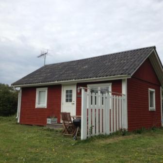 a red house with a white door and a fence at Ölands Yoga Studio & Islandshästar, Stugor & Rum in Mörbylånga