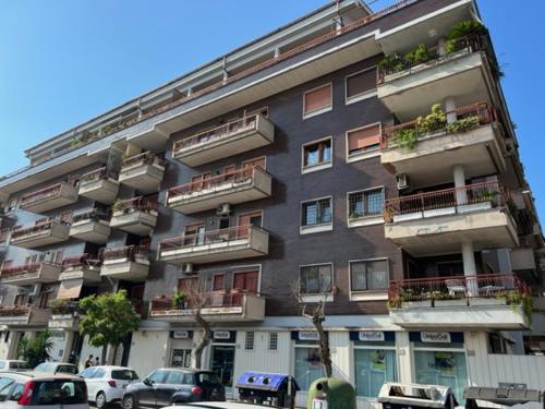 wysoki budynek z samochodami zaparkowanymi przed nim w obiekcie LA CASA DI ALICE 2 w mieście Lido di Ostia