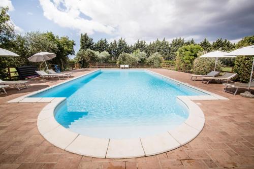 a large swimming pool with chairs and umbrellas at Agriturismo Le Giare in Bagno Roselle