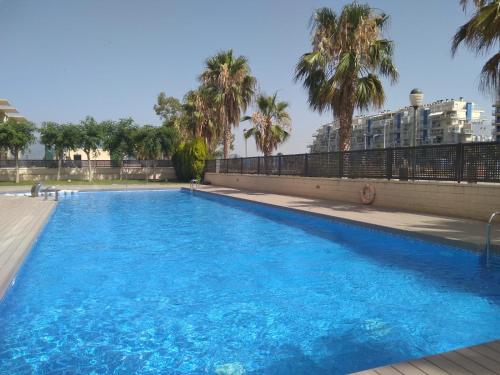 een groot blauw zwembad met palmbomen op de achtergrond bij Apartamento Moncofar playa in Moncófar