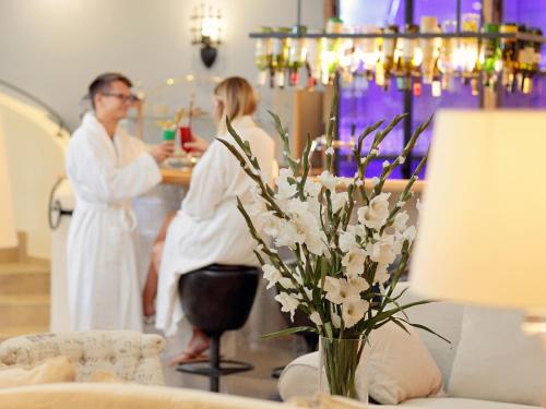 a man and a woman in a salon with a vase of flowers at INSELHOTEL Potsdam in Potsdam