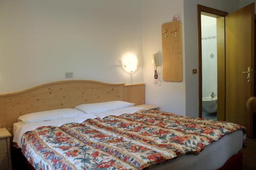 a bedroom with a large bed with a colorful quilt at Albergo Trentino in Moena