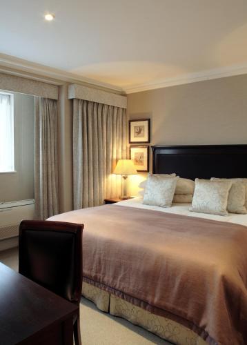 a bedroom with a large bed and a window at Cheval Knightsbridge in London