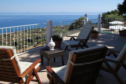 a patio with chairs and a table and the ocean at Villa DAMMUSO by Local House - private villa infinity pool & seaview in Santo Stefano di Camastra