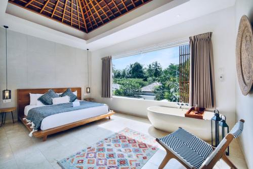 1 dormitorio con cama, bañera y ventana en Kabila Villas, en Kuta Lombok