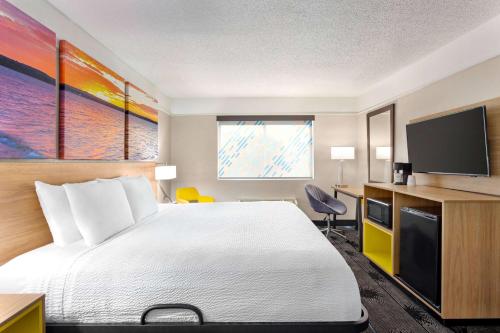 a hotel room with a bed and a flat screen tv at Days Inn by Wyndham Kansas City International Airport in Kansas City