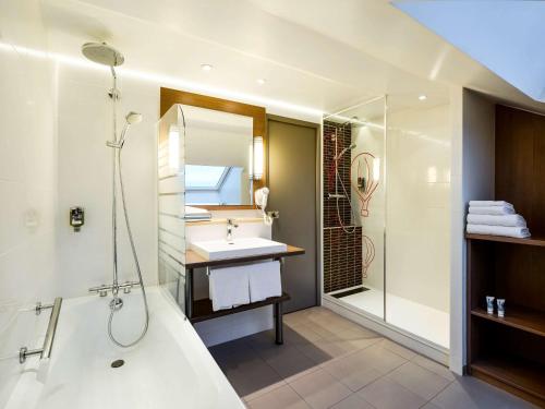 uma casa de banho com uma banheira, um lavatório e um chuveiro em Mercure Vienne Sud Chanas em Chanas