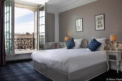 een slaapkamer met een groot bed en een balkon bij Grand Hotel De La Reine - Place Stanislas in Nancy