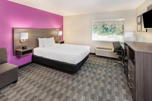 a hotel room with a bed and a purple wall at La Quinta by Wyndham Houston Southwest in Houston