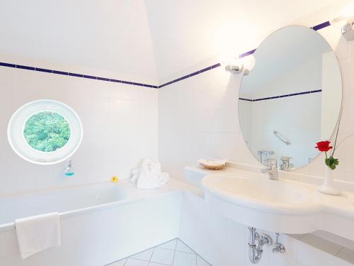a white bathroom with a sink and a mirror at INSELHOTEL Potsdam in Potsdam