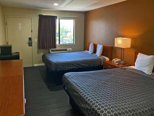 Rodeway Inn Sacramento-University Area في سكرامنتو: غرفة فندقية بسريرين ونافذة