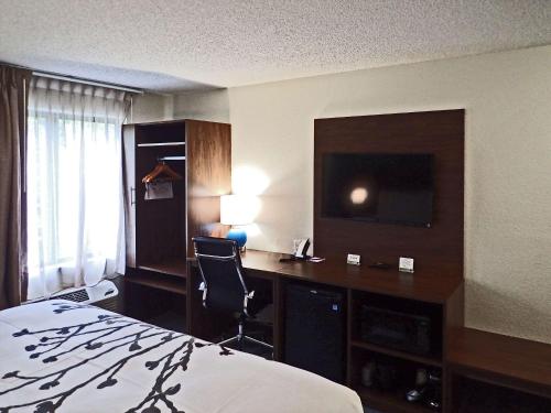 a hotel room with a bed and a desk with a television at Sleep Inn & Suites California MD in California