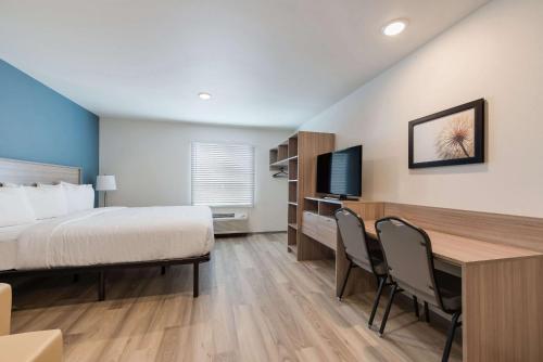 a hotel room with a bed and a desk with chairs at WoodSpring Suites Meridian in Meridian