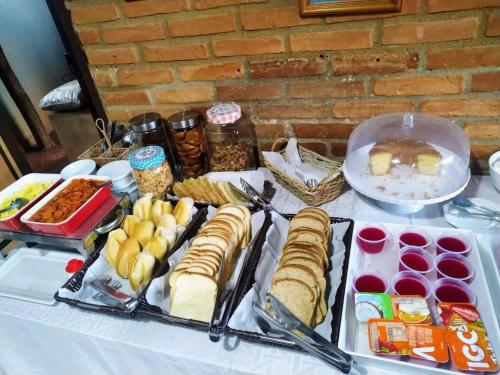 a table with sandwiches and other food on it at Galeria Hotel Pousada in Jaguariúna
