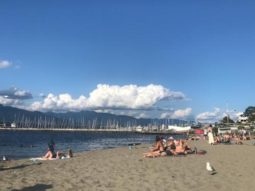a group of people sitting on the beach at walk distance to kits beach 2bedrooms only for you in Vancouver