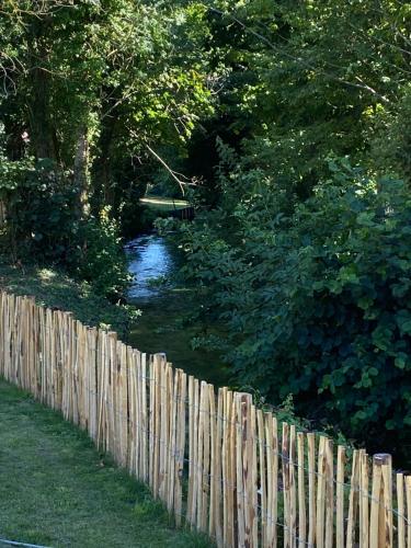 a wooden fence next to a river behind a fence at LA GRANGE in Anzin-Saint-Aubin