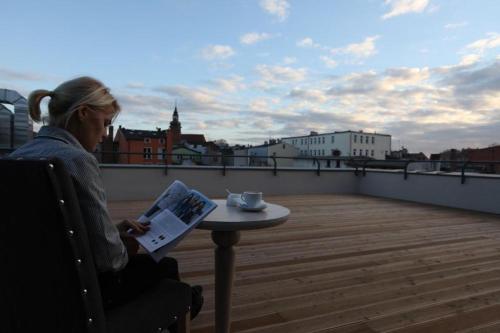 a woman sitting on a roof reading a newspaper at Hotel Browar Kościerzyna in Kościerzyna