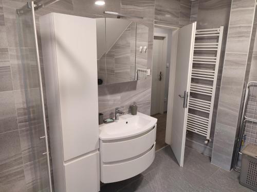 Baño blanco con lavabo y espejo en Apartman President, en Krapinske Toplice