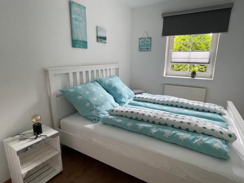 un letto bianco con cuscini blu e una finestra di Strandlächeln Lodge - Ferienwohnung mit 2 Schlafzimmern a Hohenfelde