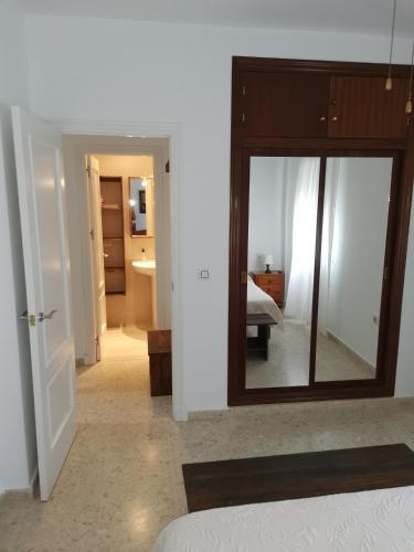 a room with a mirror and a bedroom with a bed at Apartamento con Garaje, WiFi, Centro y playa in Chipiona