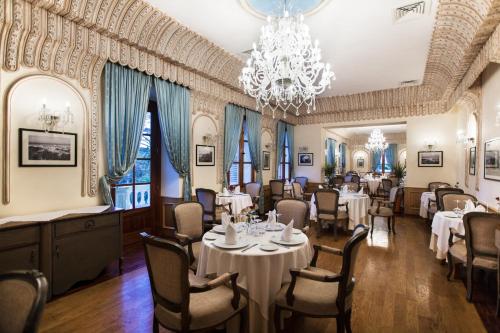 a dining room with tables and chairs and a chandelier at Grand Hotel Villa de France in Tangier