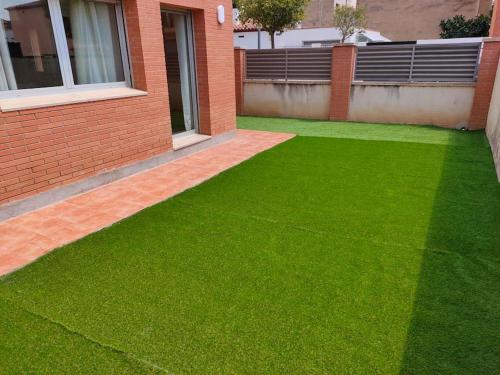 a yard with green grass next to a building at Chalet amplio con Jardín y zona barbacoa. in Reus