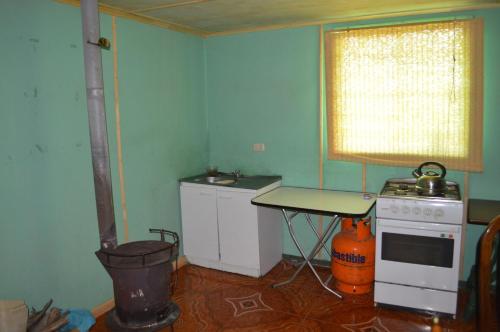 a kitchen with a stove and a table and a window at Coyunche Cabañas y Camping Laja & San Rosendo in Laja