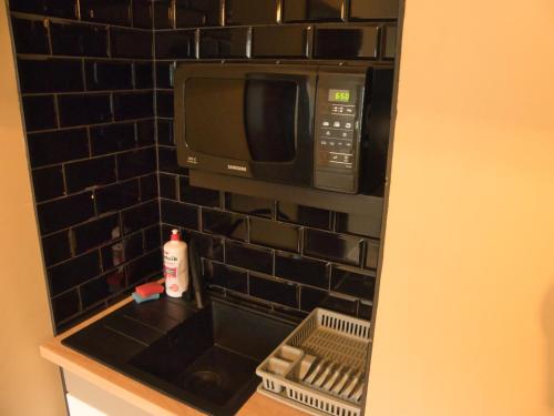 uma cozinha com um micro-ondas e uma parede de azulejos pretos em Villa Hasaba em Krościenko
