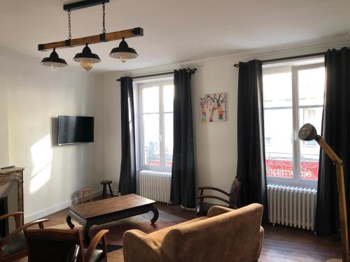 un salon avec une table, des chaises et des fenêtres dans l'établissement Les 3 p’tites pom’s, à Aleçon