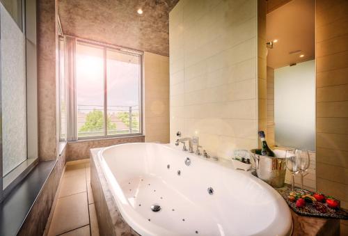 baño con una gran bañera blanca y ventana en Asam Hotel, en Straubing