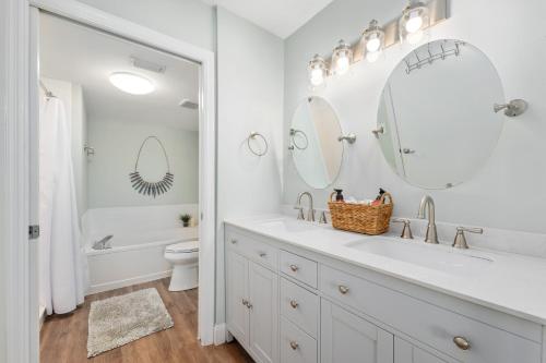 a white bathroom with a sink and mirrors at Sea Winds 501 - Corner Breeze in Ormond Beach