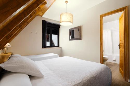 a bedroom with a white bed and a window at Hotel Deth Pais in Salardú