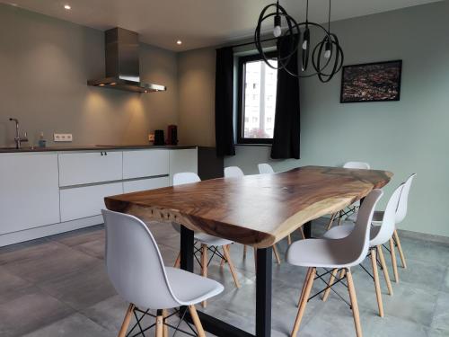 a kitchen with a wooden table and white chairs at Gasthuis Puytvoet in Sint-Niklaas