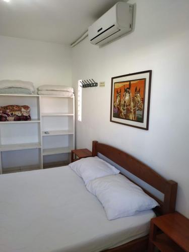 1 dormitorio con 1 cama blanca y ventilador en Residencial Praia Bombas, en Bombinhas