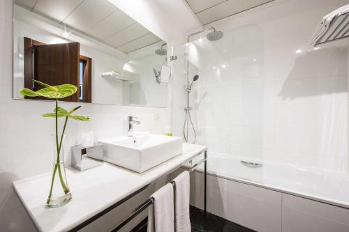a white bathroom with a sink and a tub at Apartosuites Jardines de Sabatini in Madrid