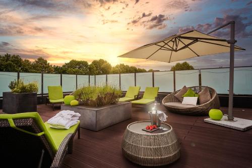 a patio with chairs and an umbrella on a deck at Asam Hotel in Straubing
