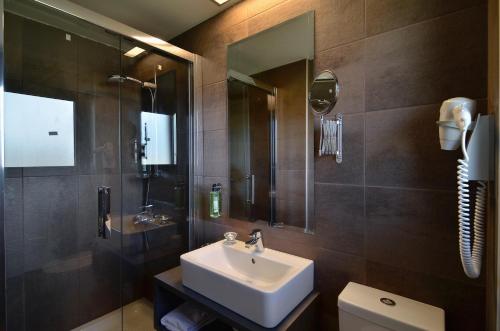 a bathroom with a sink and a mirror and a toilet at Ellopia Point Hotel in Ioannina