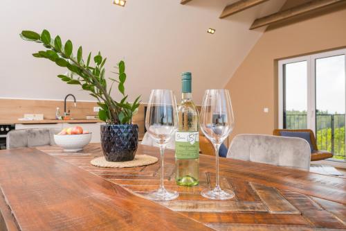 uma garrafa de vinho e dois copos de vinho numa mesa de madeira em WeinZeit Chalets em Gamlitz