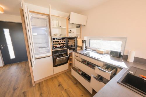 a kitchen with an open refrigerator and wooden floors at WeinZeit Chalets in Gamlitz