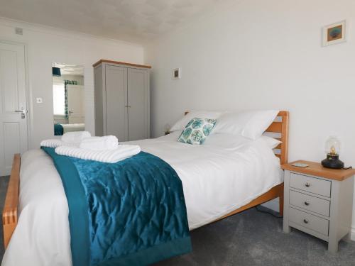 een slaapkamer met een groot wit bed en een nachtkastje bij Pelagos in Bude