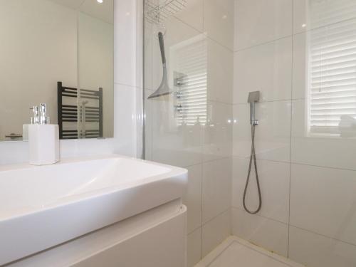 een witte badkamer met een wastafel en een douche bij Pelagos in Bude