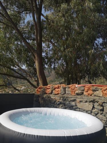 a large hot tub in front of a stone wall at Suite Zen y Cueva Refugio in Tenteniguada