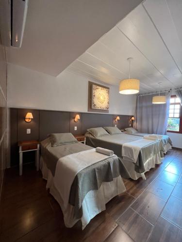 a bedroom with two beds and a clock on the wall at Chalés Pôr do Sol in Tiradentes