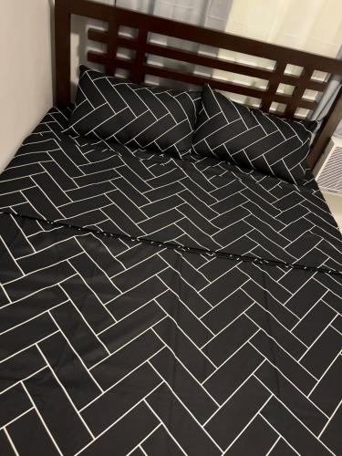 a black and white bed with black pillows on it at Modern Vacation Home Apartelle Near Centro in Iriga City
