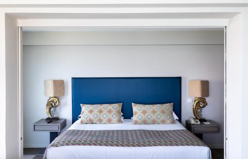 a bedroom with a large bed with a blue headboard at Best Western Premier Santa Maria in LʼÎle-Rousse