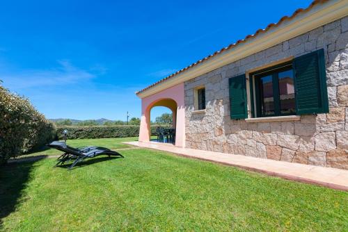 a bench sitting in the grass next to a building at Residence SardegnaSummer Li Cuppulati in San Teodoro