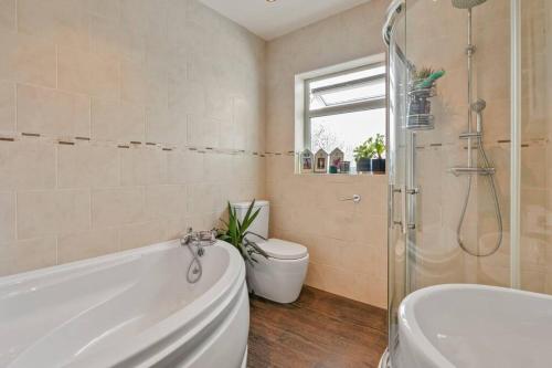 ein Bad mit einer Badewanne, einem WC und einer Dusche in der Unterkunft Quiet Seaside Getaway with Hot Tub, Herne Bay in Greenhill